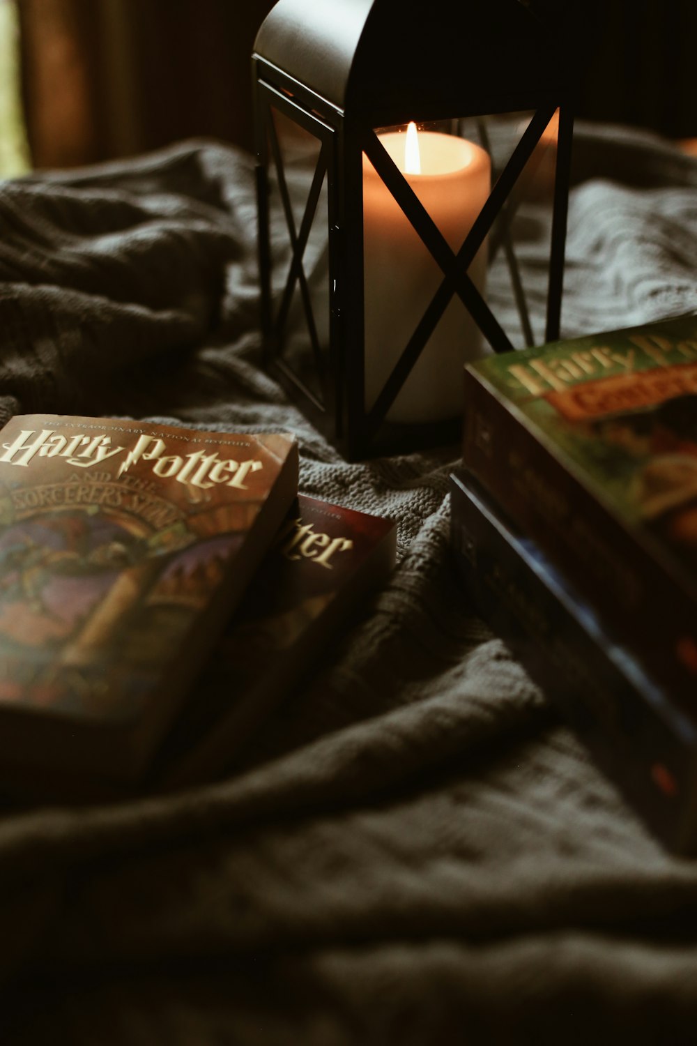 a candle sitting on top of a bed next to two books