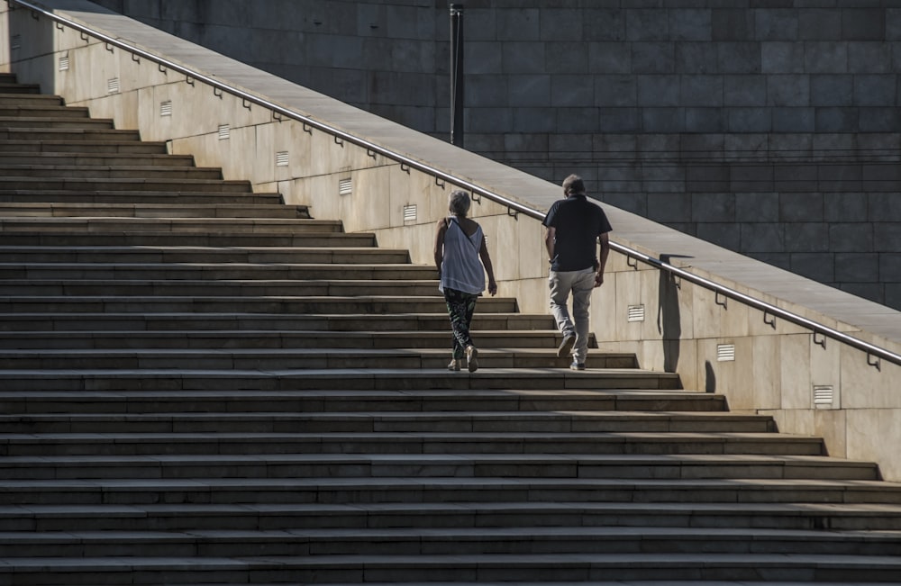 man in white shirt and black pants walking on gray concrete stairs