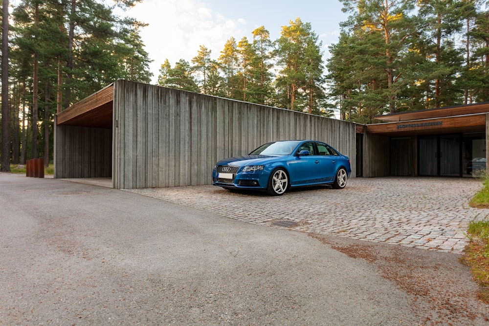 blue porsche 911 parked beside wooden wall