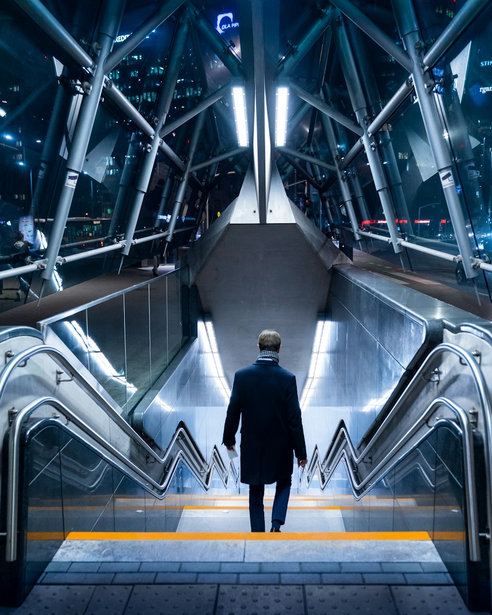 man in black suit walking on escalator