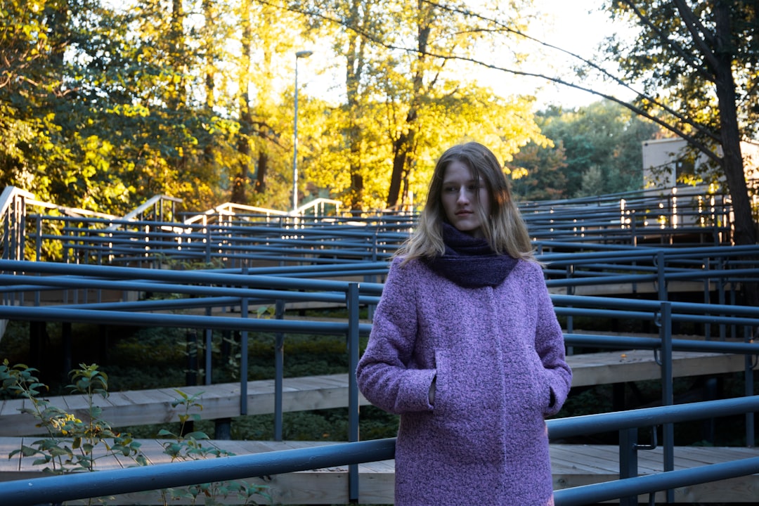 woman in gray sweater standing on bridge during daytime