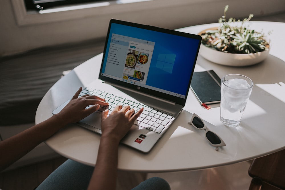 person using laptop on white table