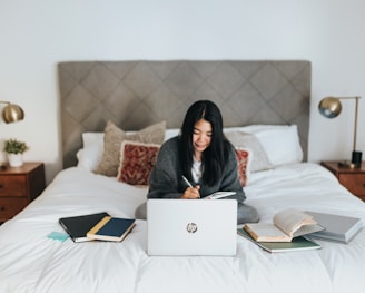 woman in black hijab sitting on bed using laptop