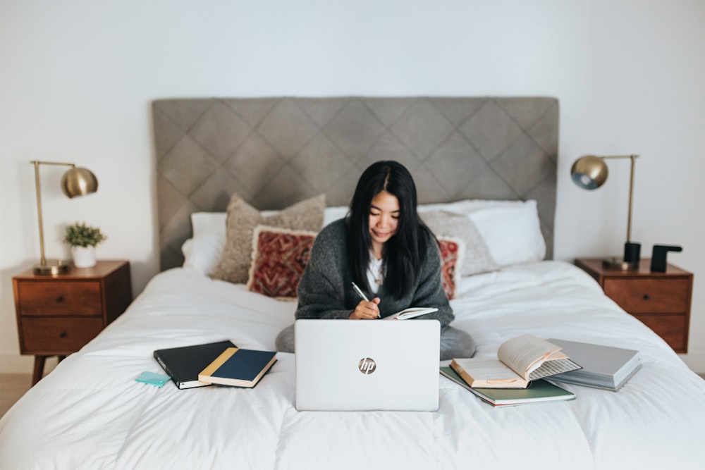 woman in black hijab sitting on bed using macbook