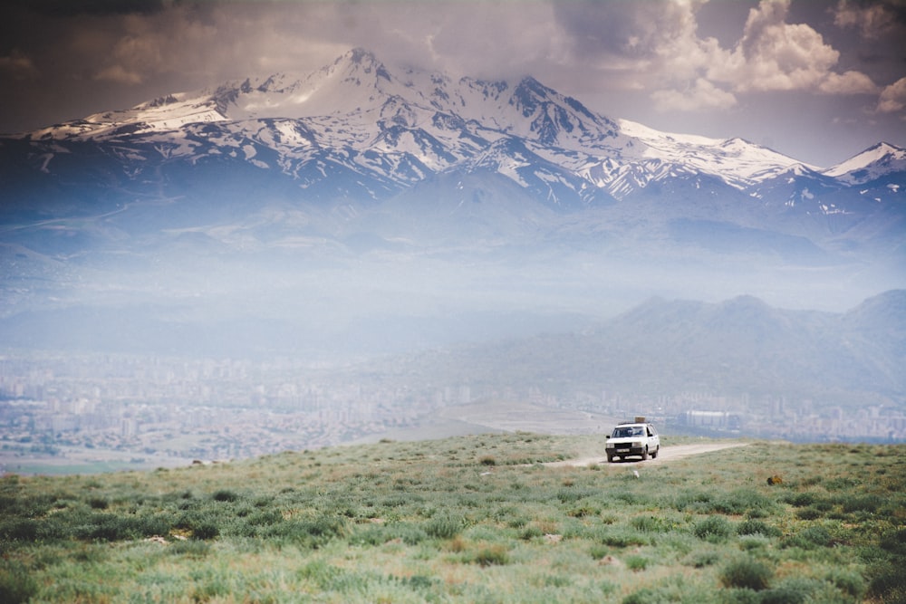 black suv on green grass field near snow covered mountain during daytime