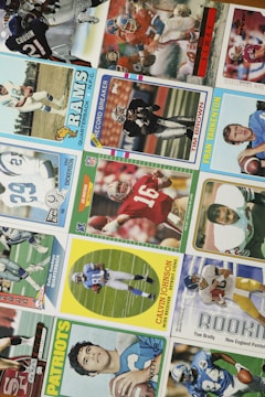 A collection of vintage football trading cards featuring various players in action poses and portrait shots. The cards display logos and names of well-known football teams like the Rams and Patriots, with some cards honoring specific achievements like 'Record Breaker'.