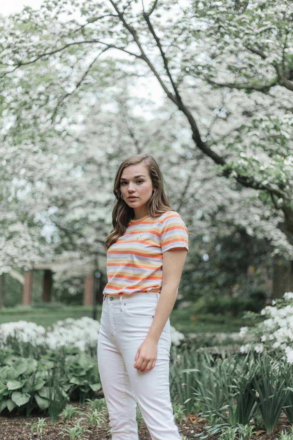 woman in white and red striped shirt standing near trees during daytime