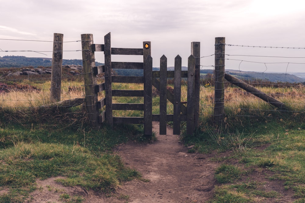 brown wooden fence on brown field under white clouds during daytime