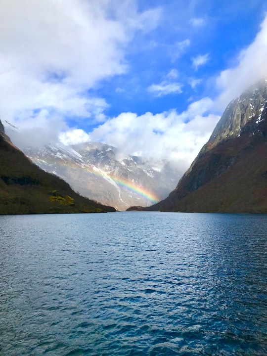 body of water near mountain under blue sky during daytime in Nærøyfjord Norway