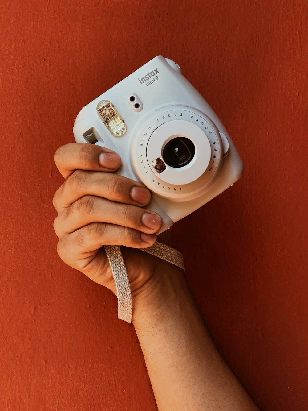 Persona che tiene in mano una fotocamera reflex digitale Canon bianca