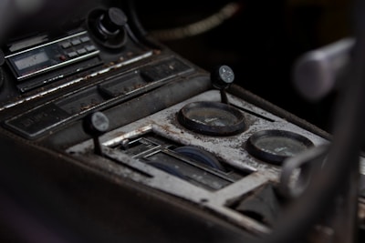Close-up of a vintage car dashboard showing worn controls and gauges.
