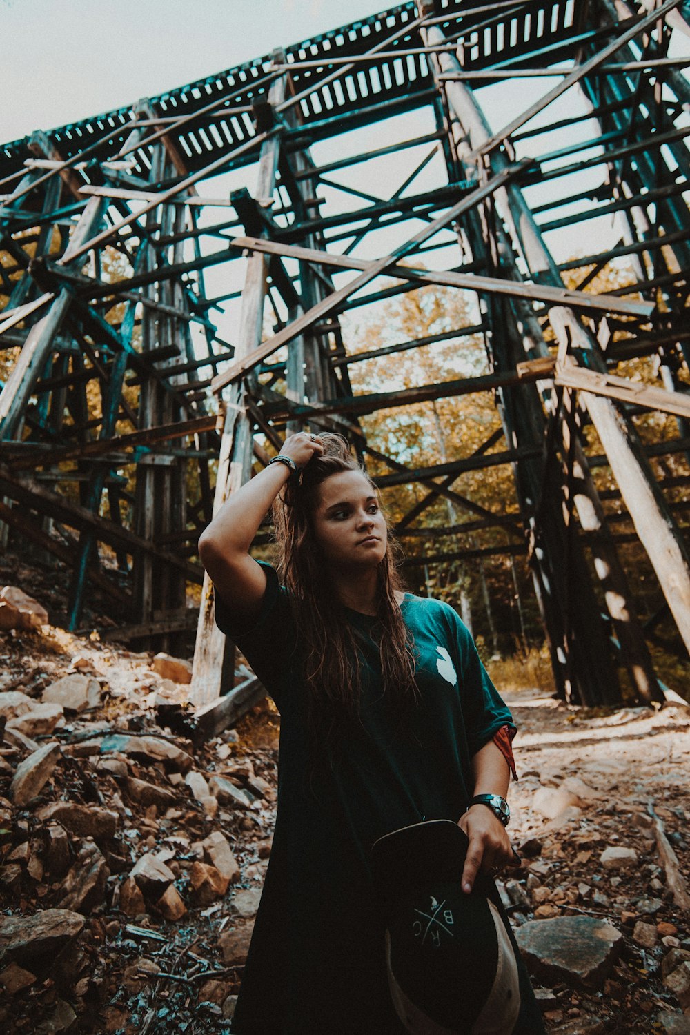 woman in black and blue crew neck t-shirt standing near brown wooden ladder during daytime