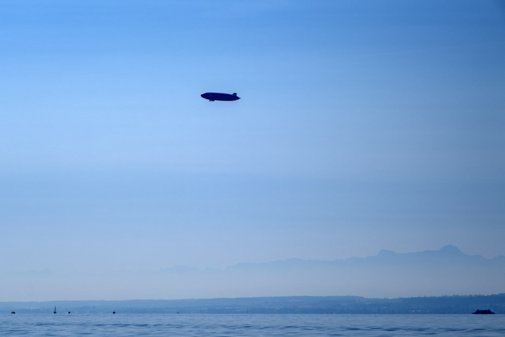 black airplane flying over the sea during daytime