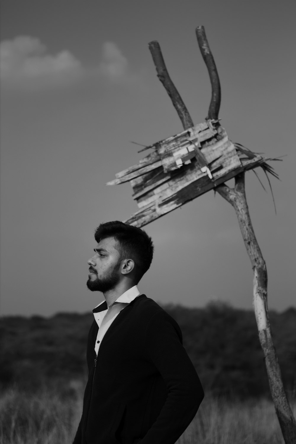 man in black suit holding a wooden cross