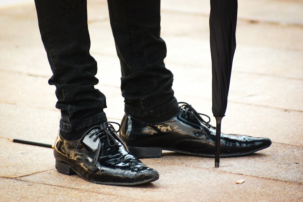 person in black leather boots standing on brown sand