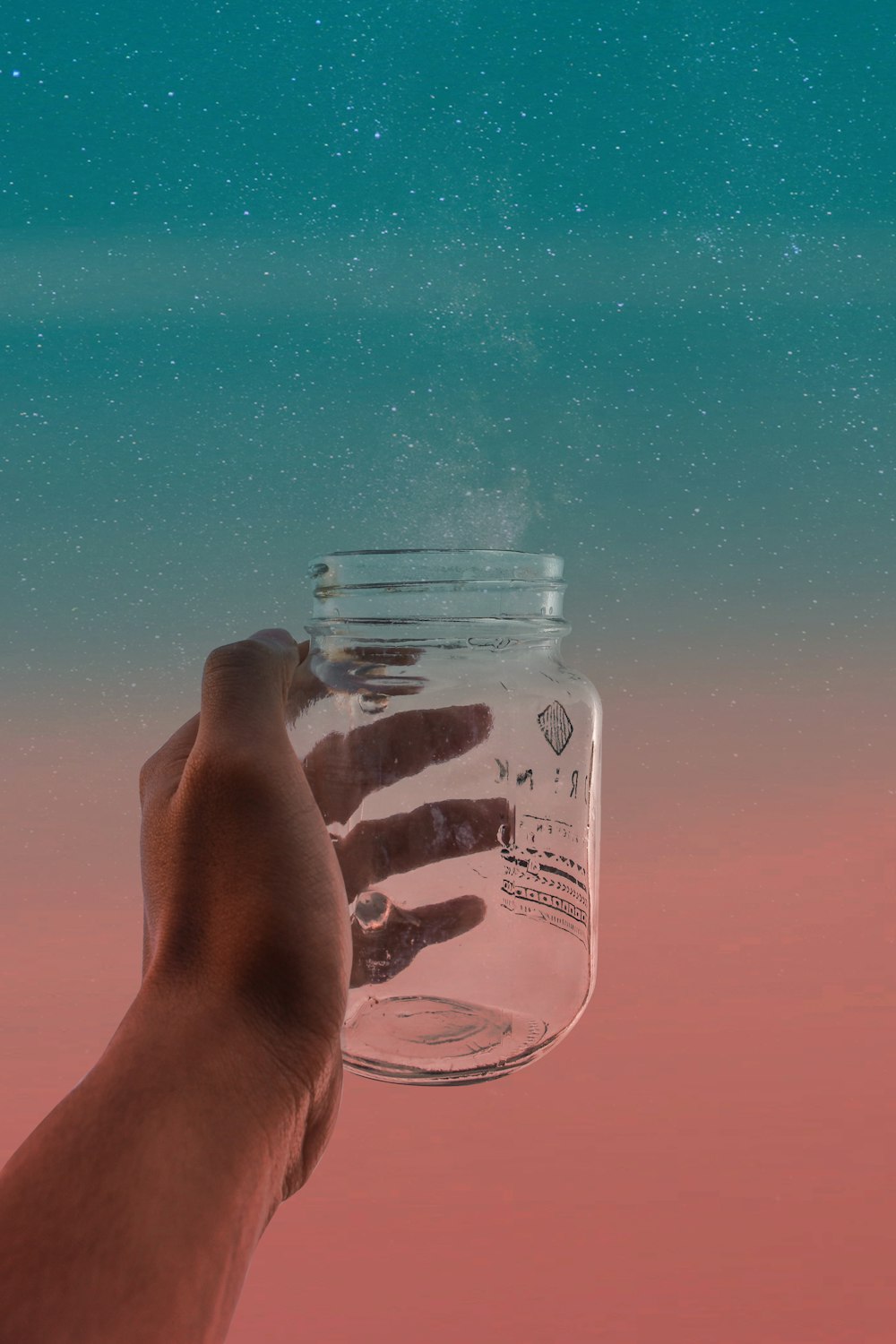 person holding clear glass jar