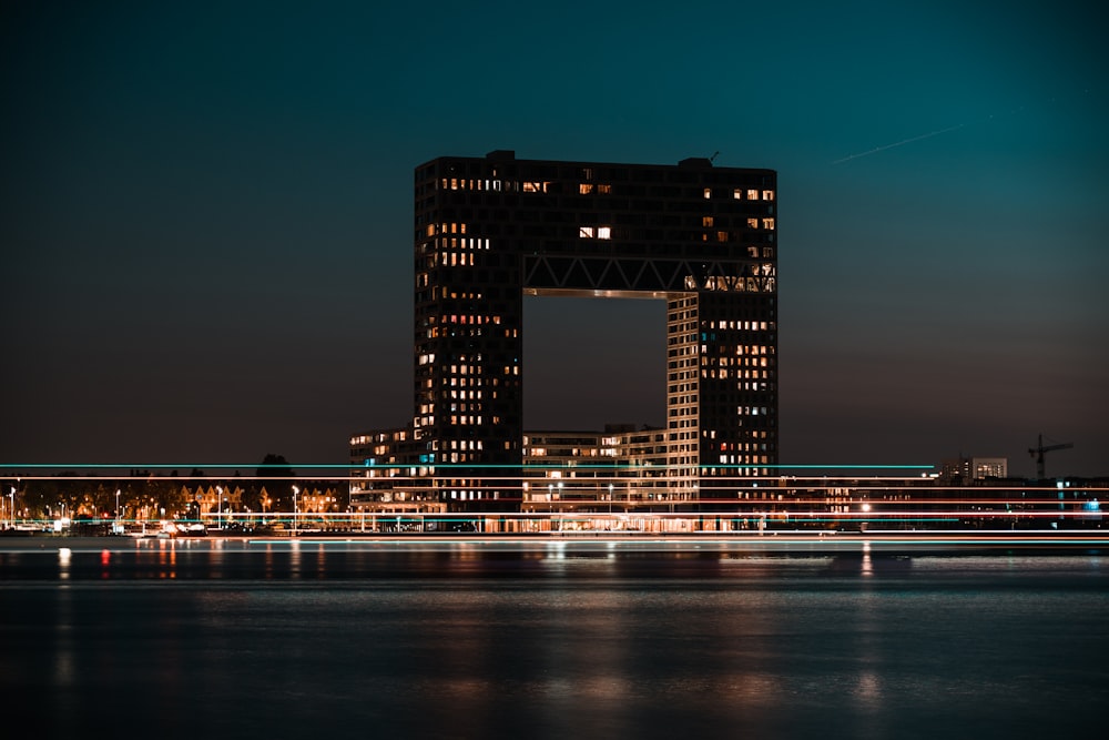 black lighted high rise building near body of water during night time