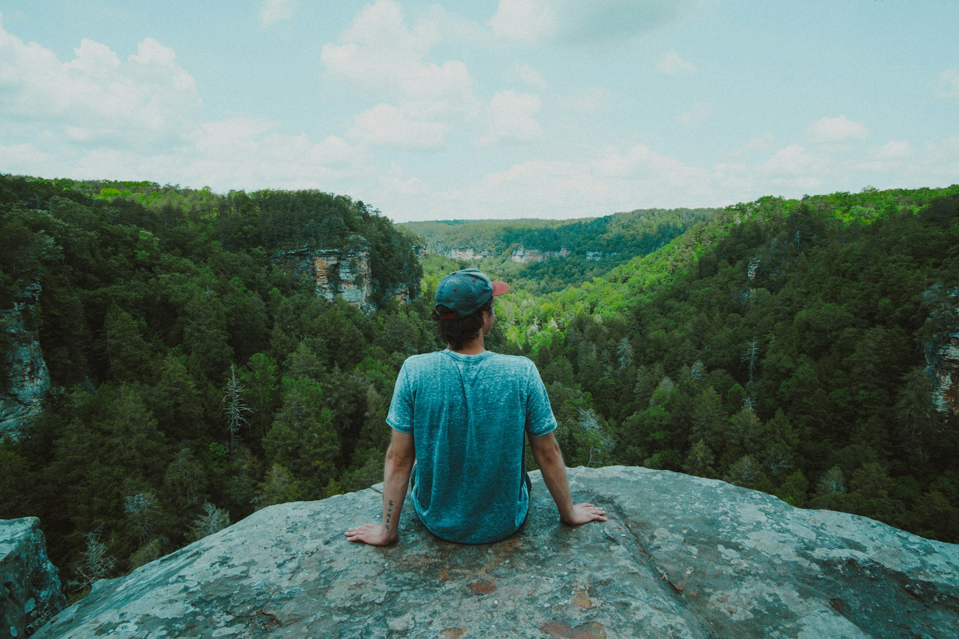 woman in blue dress sitting on rock formation during daytime