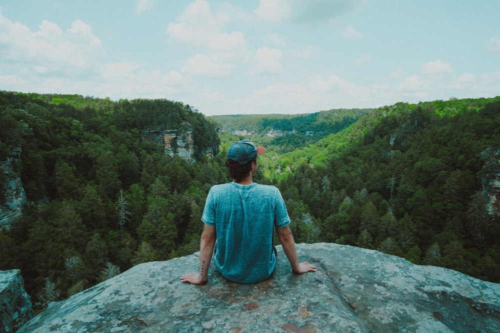 woman in blue dress sitting on rock formation during daytime