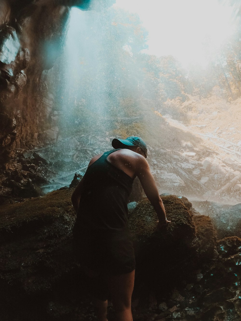 Hombre con camiseta sin mangas negra y pantalones cortos negros de pie en Brown Rock cerca del río durante el día