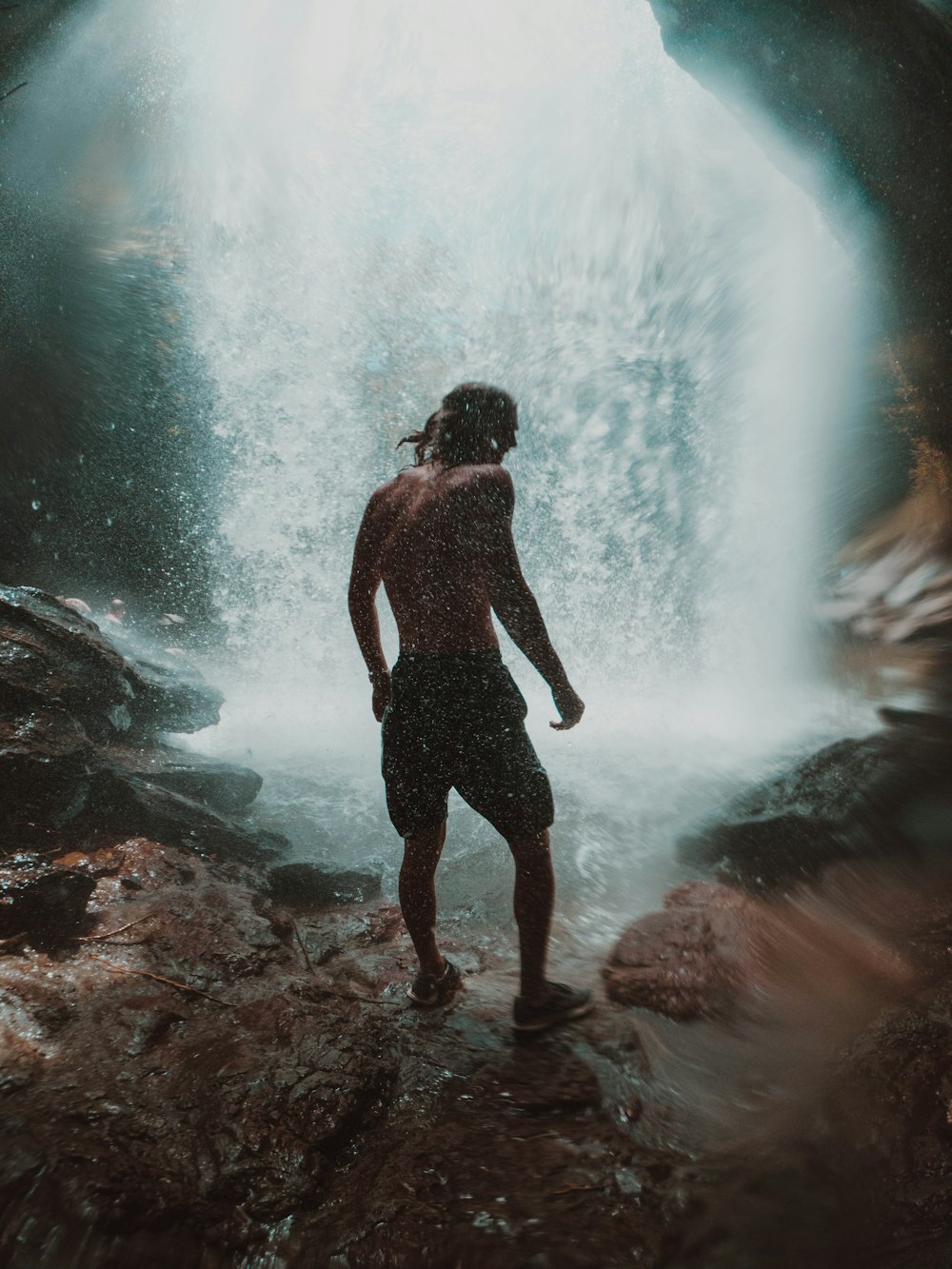 man in black shorts standing on rocky shore during daytime