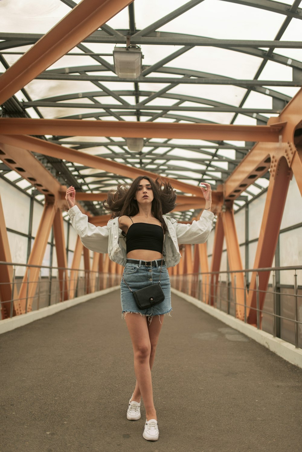 woman in white long sleeve shirt and blue denim shorts standing on brown wooden bridge