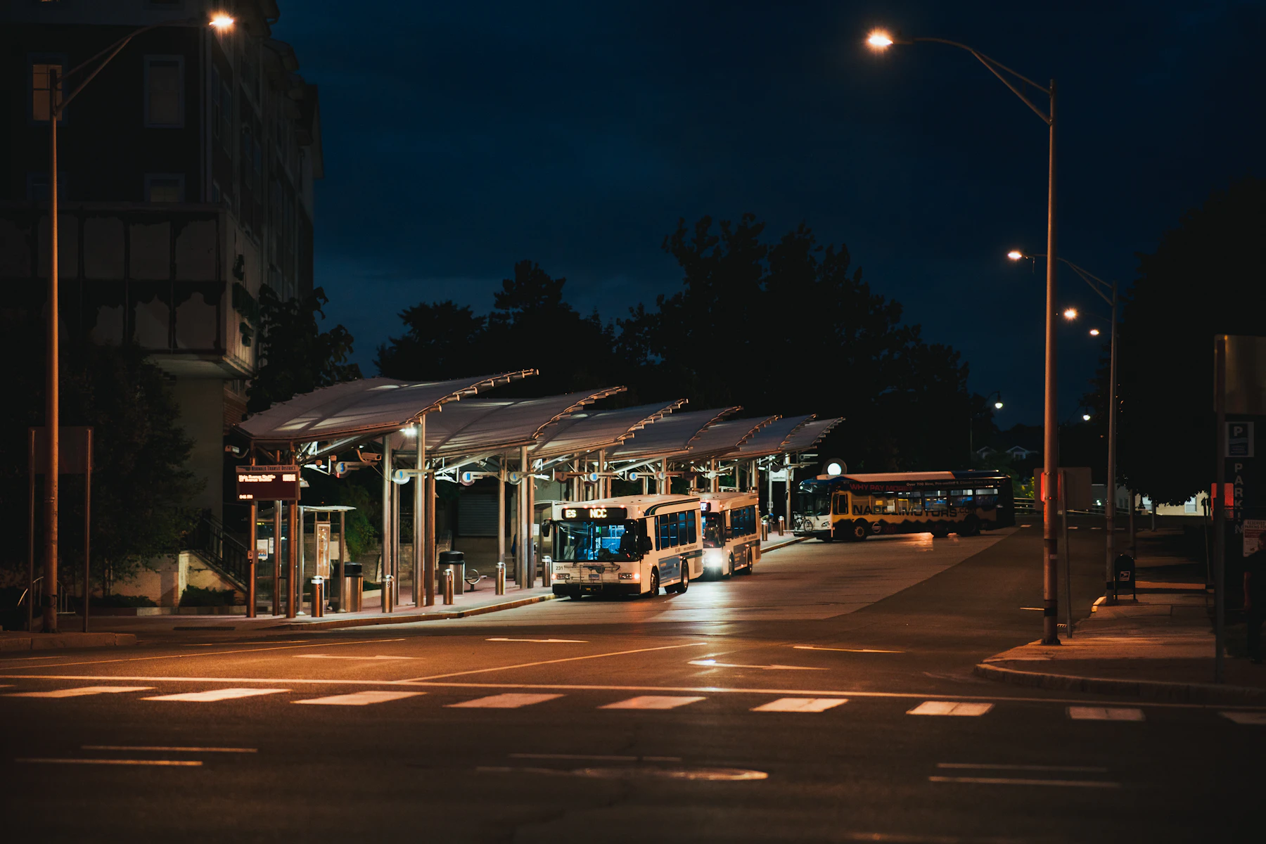 A tram on a wet street at night beneath streetlights