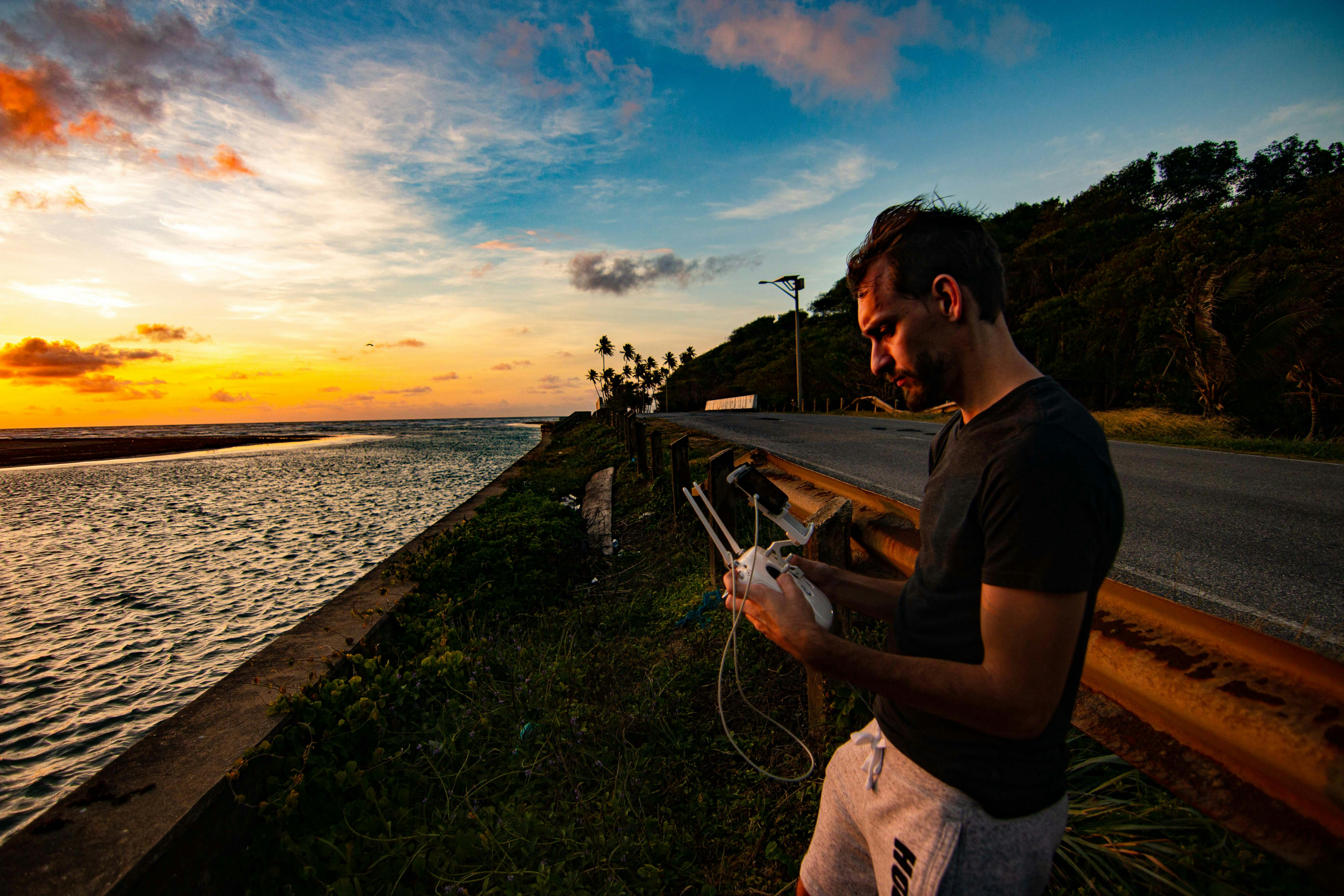 man in black t-shirt holding fishing rod standing on dock during sunset