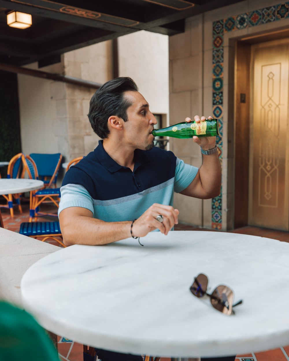 woman in blue and black stripe shirt drinking from bottle