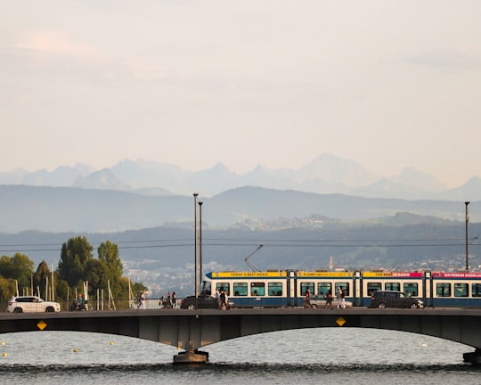 yellow and black train on bridge over river in Zürich Switzerland