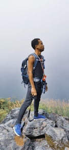 man in blue and black backpack standing on green grass field during daytime