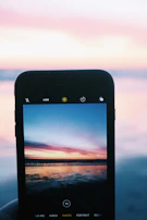 Close-up of a Samsung Galaxy J7 displaying a calming ocean sunset wallpaper with warm hues.