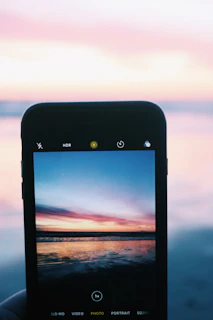 Close-up of a Samsung Galaxy J7 displaying a calming ocean sunset wallpaper with warm hues.