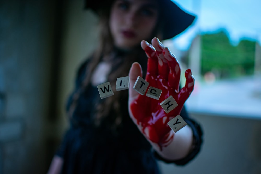 woman in black hat holding red heart shaped ornament