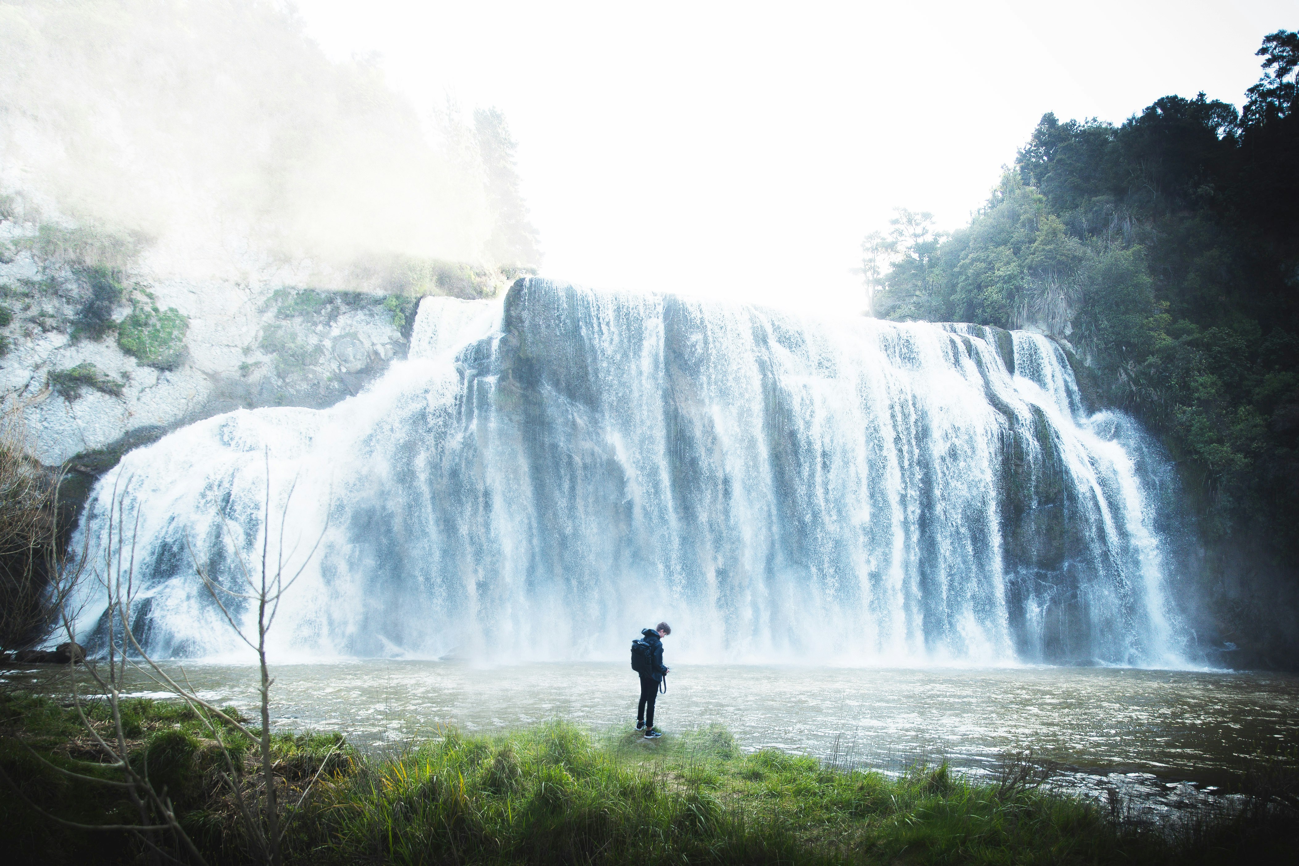 person standing near waterfalls during daytime