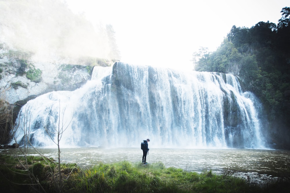 person standing near waterfalls during daytime
