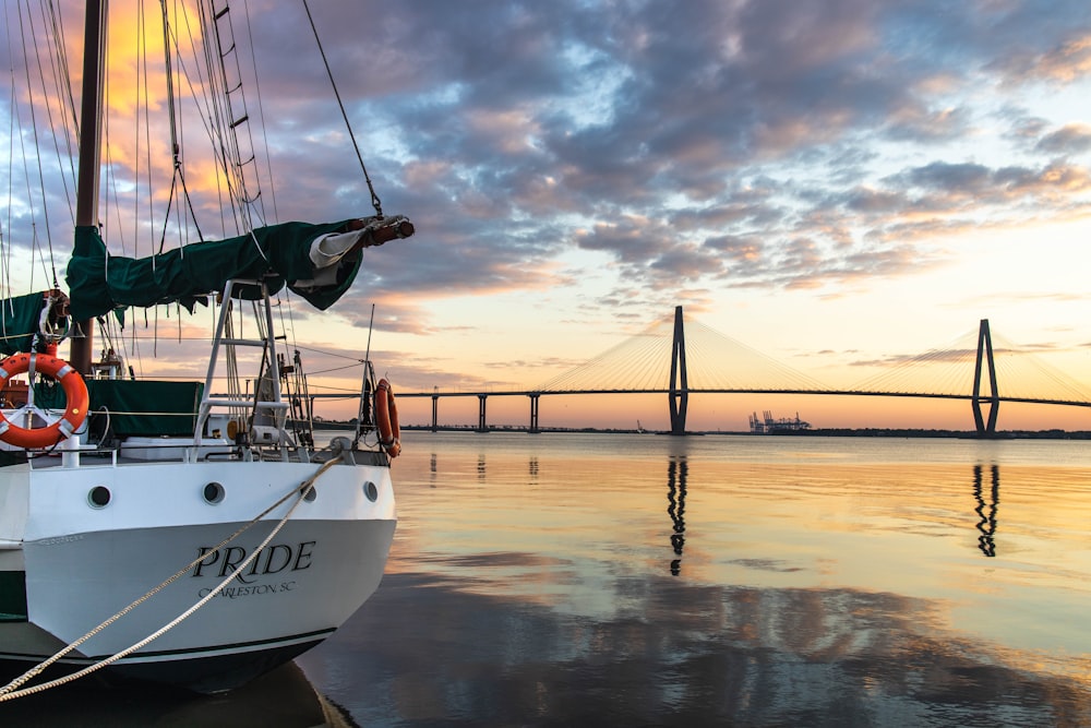 a sailboat docked at a dock with a bridge in the background