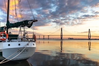 a sailboat docked at a dock with a bridge in the background