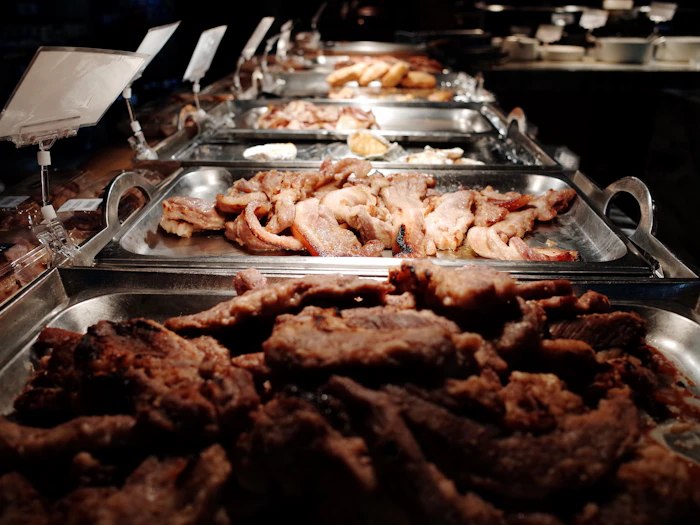 Pečeno meso v gastro posodah na samopostrežnem pultu