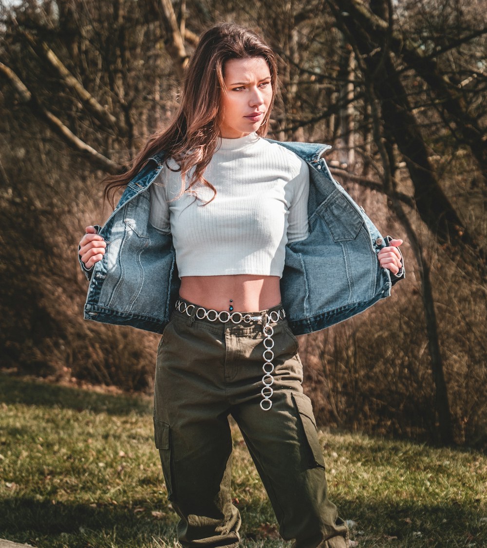 woman in blue denim jacket and black pants standing on green grass field