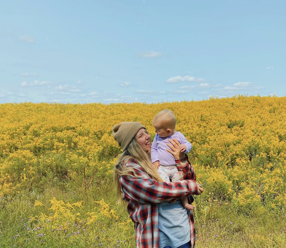 man in brown and white plaid shirt standing on yellow flower field during daytime