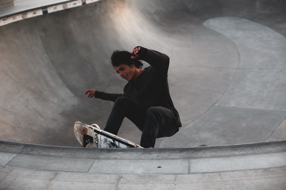 man in black long sleeve shirt and black pants sitting on skateboard