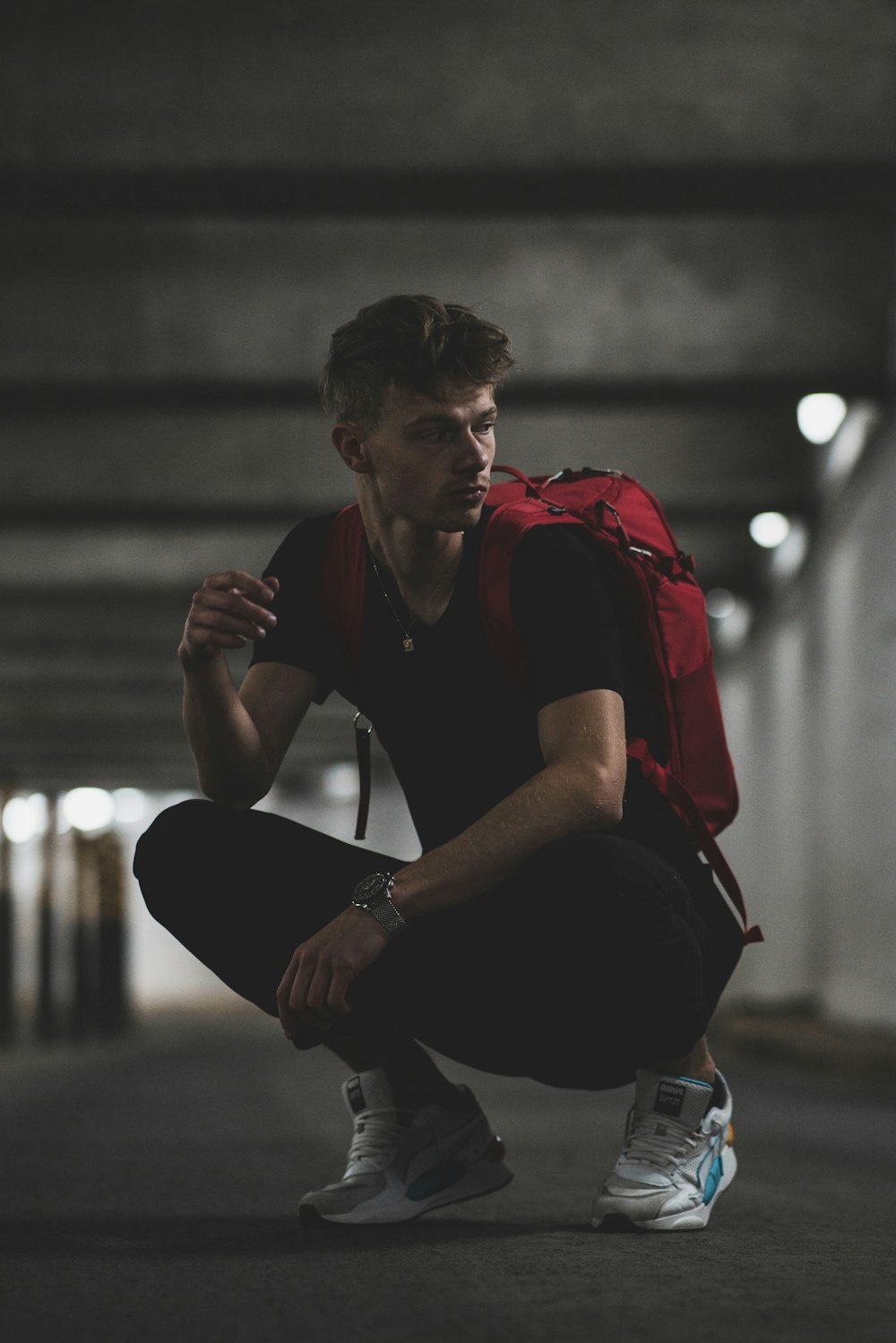 man in black and red jacket and black pants sitting on concrete bench