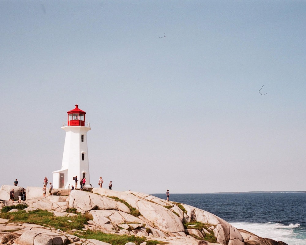 white and red lighthouse on brown rocky shore under blue sky during daytime