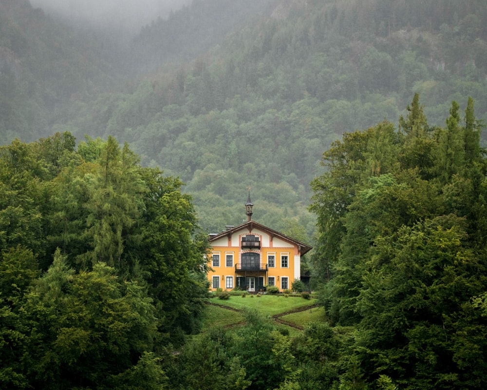 brown and white concrete house surrounded by green trees during daytime