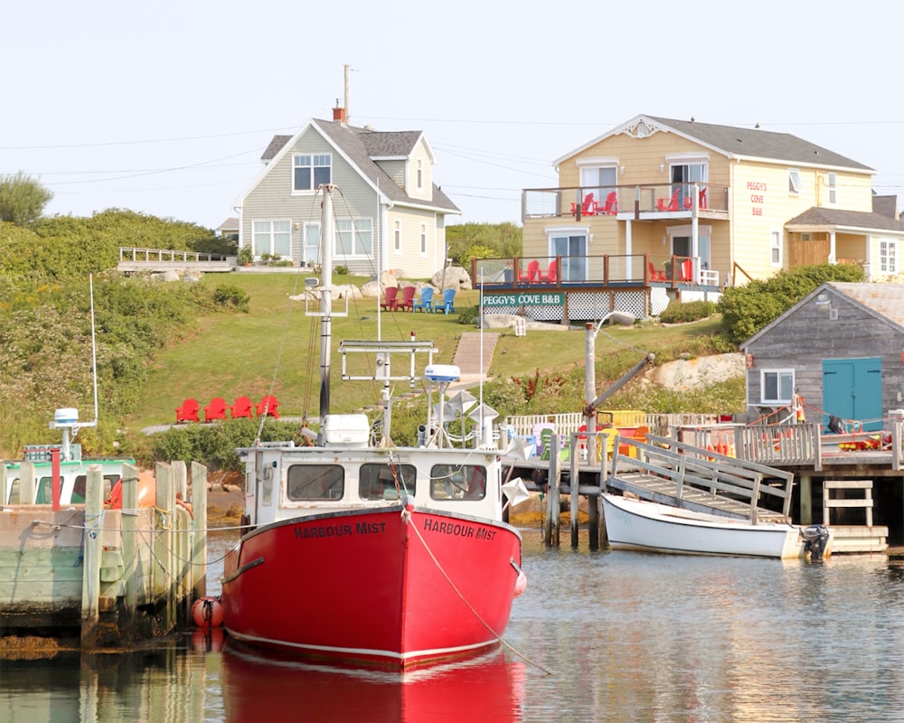 red and white boat on body of water near houses during daytime