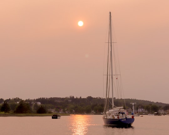 white sail boat on body of water during sunset in Lunenburg Canada