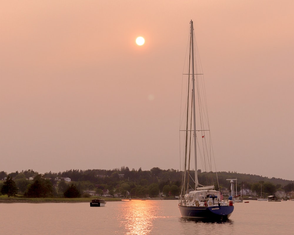 Weißes Segelboot auf dem Gewässer bei Sonnenuntergang