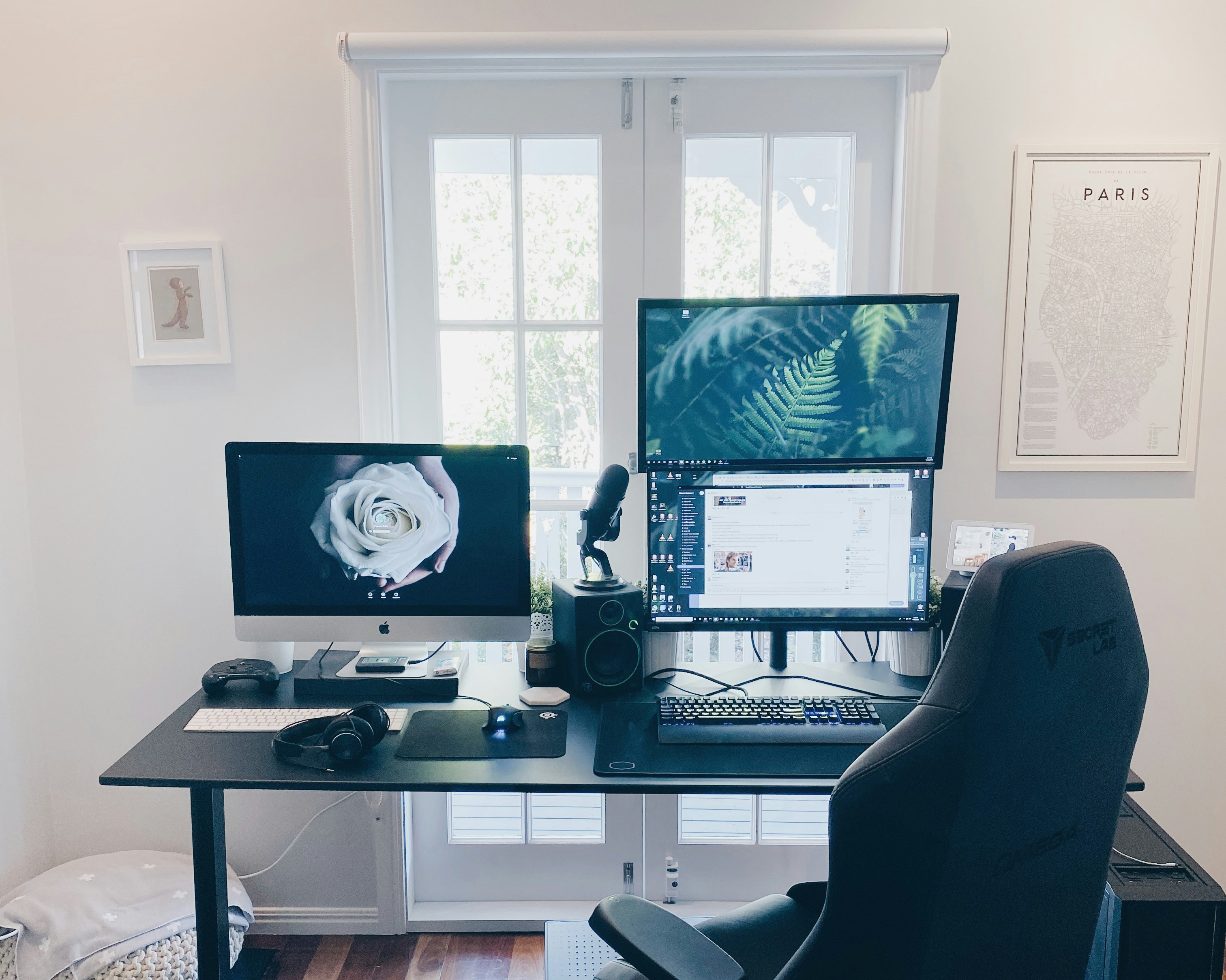 A clean, organized home office desk featuring a laptop, a small plant, and a notebook in a bright, sunlit family living room.