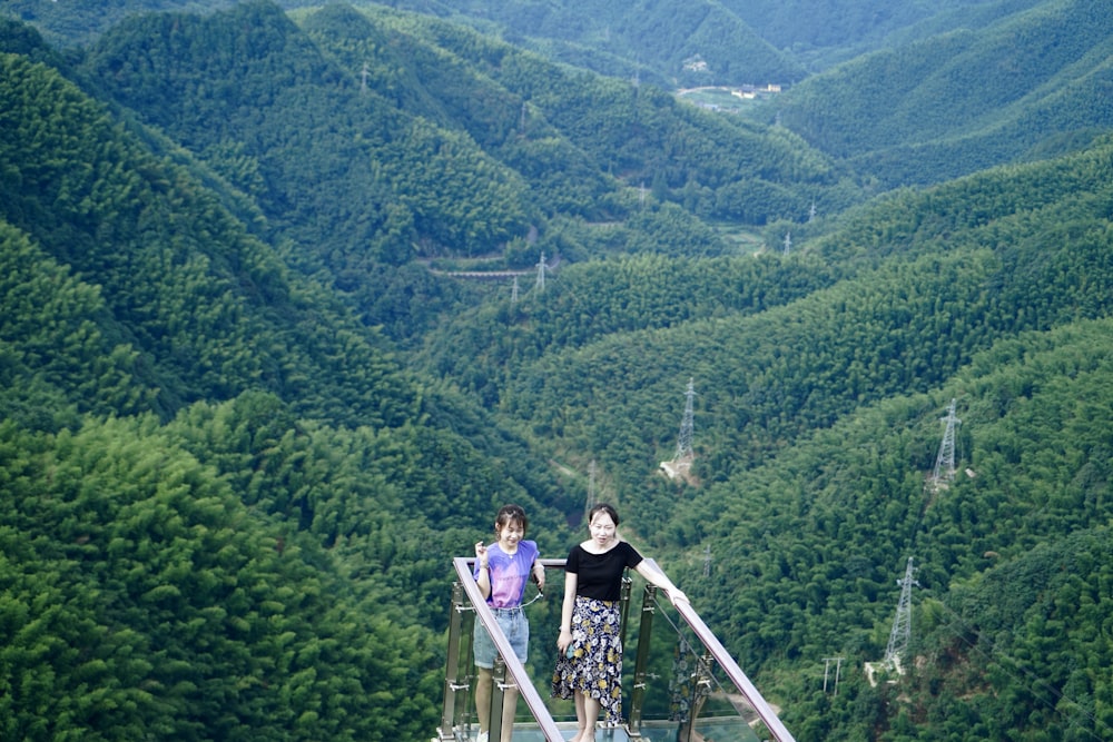 woman in pink jacket standing on gray metal bridge during daytime